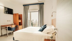 A hotel room with a bed, a desk, a TV, and a view of the outside. - Hotel Mediterraneo (Santa Marinella)