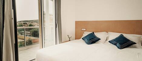 A hotel room with a large bed, a wooden headboard, and a view through a sliding glass door.