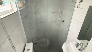 A small bathroom with a toilet, a sink, and a shower enclosure. - Furnished studio apartment in Vila Amália, North Zone (São Paulo)