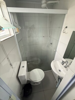 A small bathroom with a toilet, a sink, and a shower enclosure. - Furnished studio apartment in Vila Amália, North Zone (São Paulo)