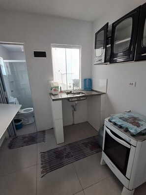 Uma cozinha compacta com pia, janela, micro-ondas e forno pequeno.