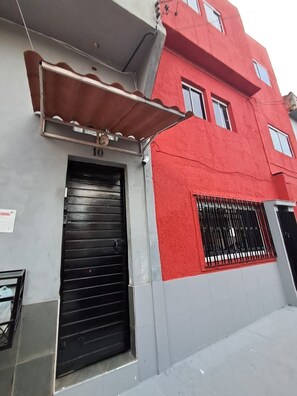 Um edifício com fachada vermelha, porta de garagem preta e toldo de metal.