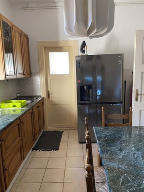 A kitchen with wooden cabinets, a stainless steel refrigerator, a water dispenser, and a marble countertop. - Uz obalu mora, luksuzna villa sa jacuzzyjem, (Hvar)