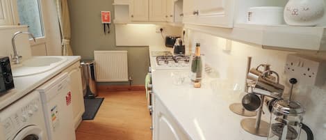 Una cocina equipada con lavadora, radiador, un reloj y cafetera.
