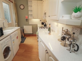 Una cocina equipada con lavadora, radiador, un reloj y cafetera.