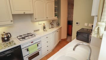 A kitchen with white cabinets, a gas stove, a sink, and a microwave.