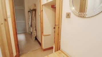 A hallway with a wooden door, a mirror with a mosaic frame, and a carpeted floor.