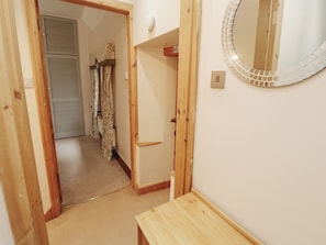 A hallway with a wooden door, a mirror with a mosaic frame, and a carpeted floor. - The Haven (Morecambe)