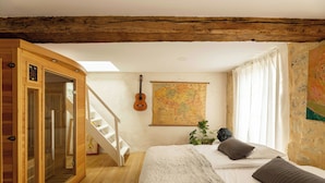 Une pièce aménagée comme un chalet en bois, avec un lit, une carte accrochée au mur, une guitare et un escalier.