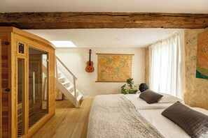Ein holzgetäfeltes Zimmer im Blockhausstil mit einem Bett, einer Karte an der Wand, einer Gitarre und einer Treppe.