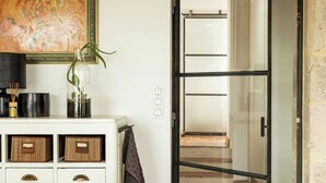 Une pièce avec un meuble blanc, une porte vitrée donnant sur un escalier et un tableau accroché au mur.