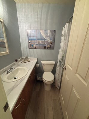 Een badkamer met een wastafel, toilet en een raam met uitzicht op het strand.