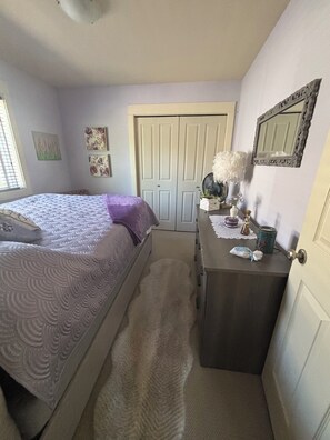 Een slaapkamer met een bed, een kaptafel, een spiegel en een deur.