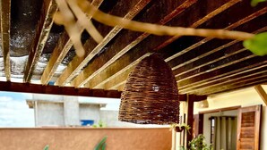A poolside area with a table, a hanging light fixture, and a view of a building in the background.