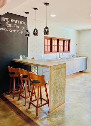 A modern kitchen with a chalkboard wall, pendant lights, wooden stools, and a built-in island.