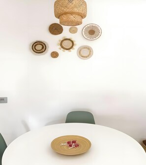 Ruokailutila, jossa on pyöreä pöytä, tuolit ja seinään kiinnitetty valaisin.