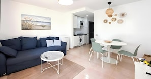 A modern living room with a sofa, a round coffee table, and a dining area with a table and chairs. - Oasis Dunas Eguzkilore Sun & Pool by B-Rent: Your Ideal Retreat in Corralejo (Corralejo)