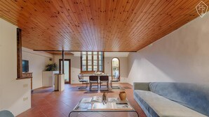 A spacious living area with a high wooden ceiling, a dining area with a table and chairs, and a kitchen in the background. - San Frediano, terrace, patio, and heating pool (Firenze)