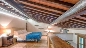 A bedroom with a bed, bedside table, lamp, and a wooden ceiling. - San Frediano, terrace, patio, and heating pool (Firenze)