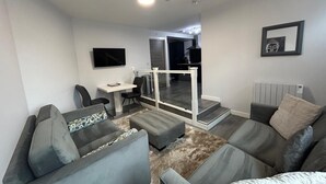 Ett modernt vardagsrum med grå soffor, ett litet bord och en tv.