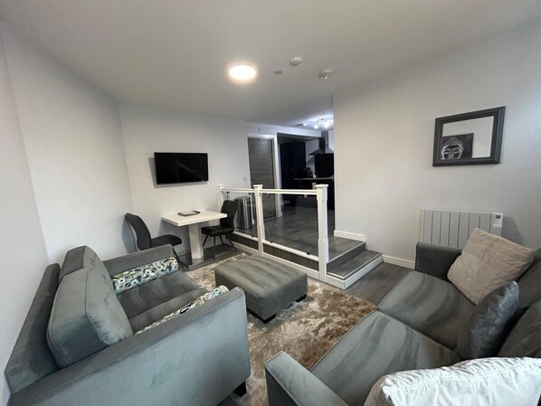 A modern living room with grey sofas, a small table, and a TV.