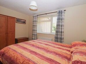 A bedroom with a bed, a wardrobe, a radiator, and a window with curtains. - 51 Colin Mclean Road (Dereham)