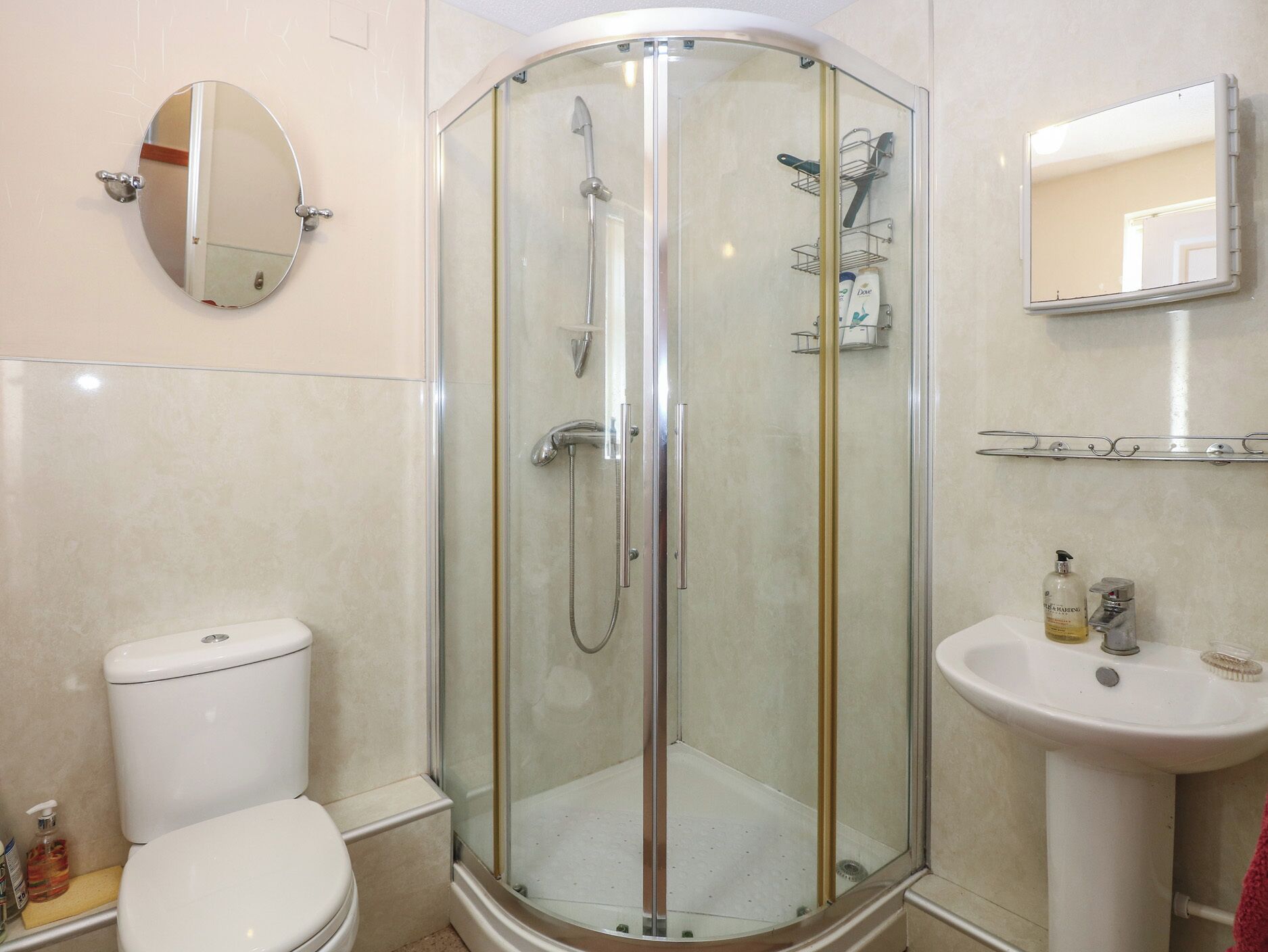 A modern bathroom with a glass-enclosed shower, a toilet, a sink, and a mirror.