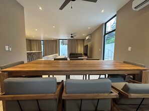 Un espace repas moderne avec une table en bois et des chaises à revêtement gris, un ventilateur de plafond et un appareil de climatisation.