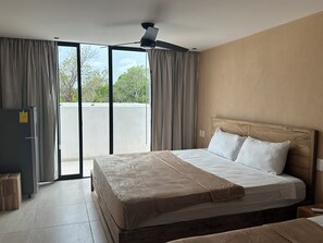 A hotel room with a bed, a ceiling fan, a sliding glass door, and a small table. - Spacious 4BR Villa in Tulum (Tulum)