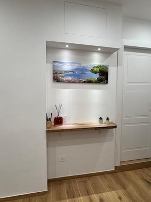 Um interior moderno com uma estante de madeira, um quadro de paisagem costeira e uma porta branca.