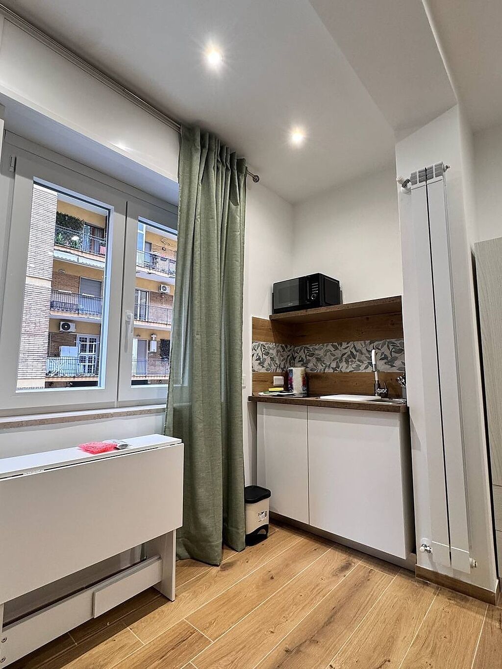 A compact kitchen with a window, a microwave, a sink, and a cabinet.