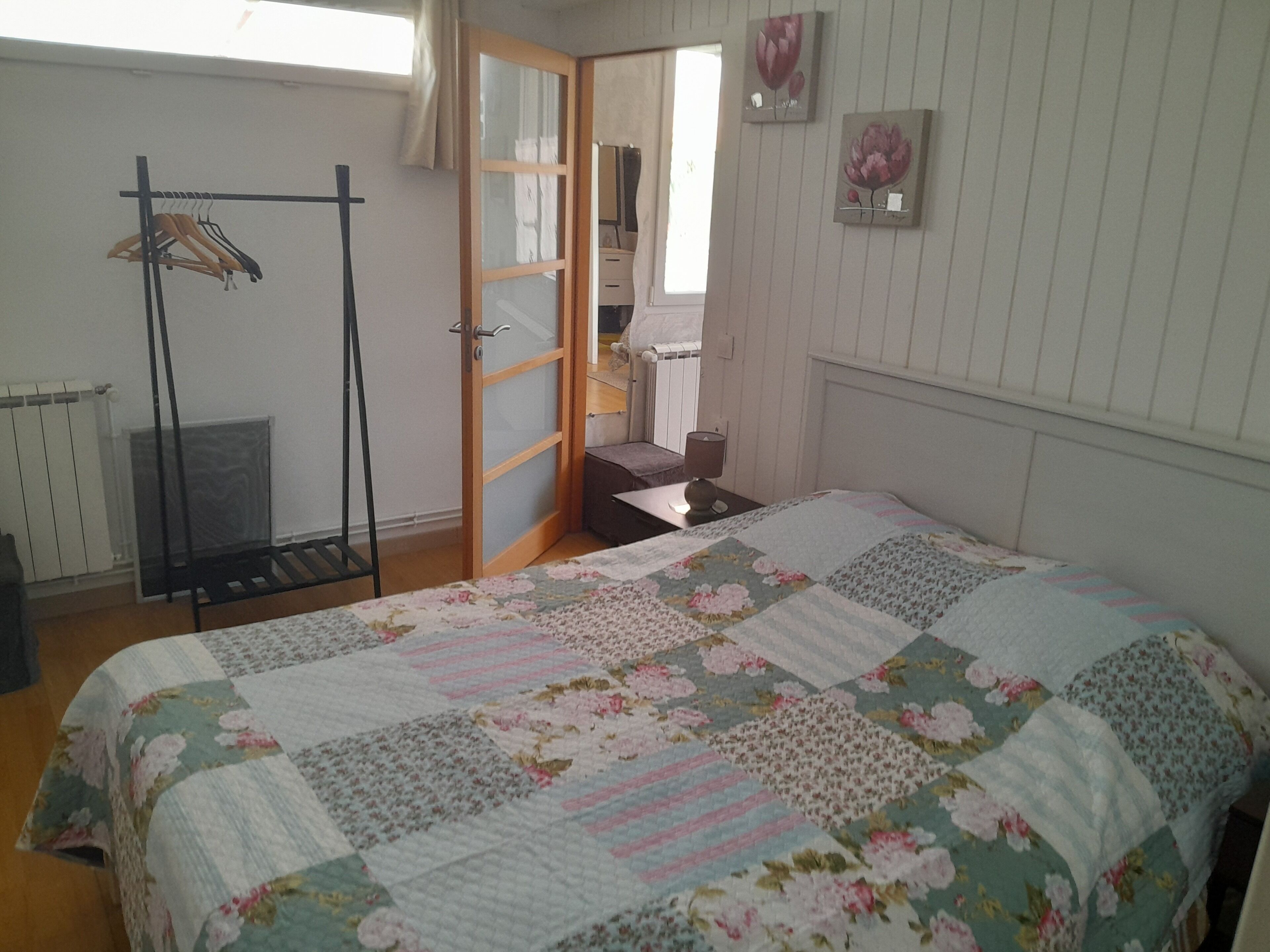 Ein Schlafzimmer mit einem Bett, einer Holztür, einem Heizkörper und einem Fenster.
