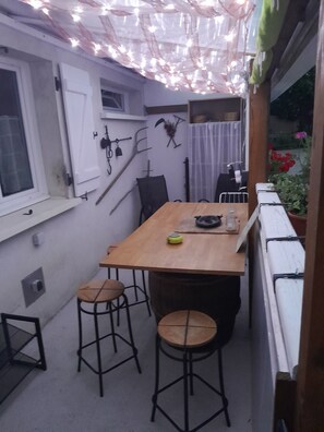 Pieni ruokailutila, jossa on puinen pöytä ja kaksi jakkaraa, ikkuna, jossa on verhot, ja seinälle kiinnitetty naulakko.