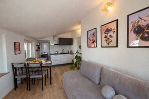 A compact living space with a dining area, kitchenette, and a sofa. - La finestra sul Lago by Theater Home - with marvellous lake view (Tignale)