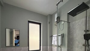 Ein Badezimmer mit einer Duschkabine, einem Waschbecken, einer Toilette und einem Spiegel.