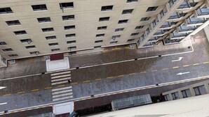 Ein Hochhaus mit mehreren Etagen, einer zentralen Treppe und einem Parkplatz mit Fahrbahnmarkierungen.