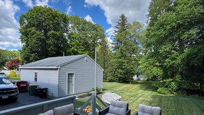 A deck with outdoor furniture, a covered grill, and a house in the background.