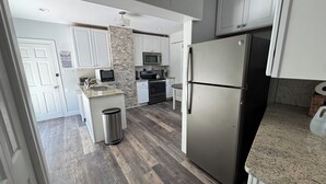 A modern kitchen with white cabinets, a stainless steel refrigerator, a microwave, and a stove.