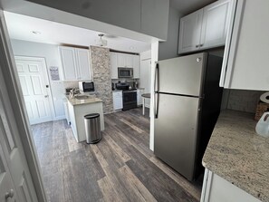 Una cocina moderna con armarios blancos, un refrigerador de acero inoxidable, un microondas y una estufa.