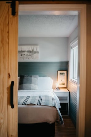 Une chambre à coucher avec un lit, une table de chevet et un tableau encadré au mur.