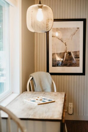 A dining area with a table, chair, pendant light, framed picture, and a power outlet.