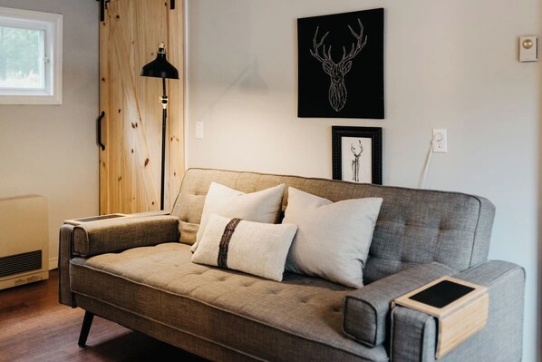 A modern living room with a grey sofa, a black floor lamp, and artwork on the wall.