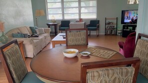 A living room with a round table, two chairs, a sofa, a television, and a bookshelf. - Classic Florida 2-bedroom house with AC in quaint DeLand (DeLand)