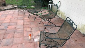 Een terras met metalen stoelen en een waterslang.