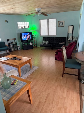 A living room with a television, a ceiling fan, a sofa, a coffee table, and a bookshelf. - Classic Florida 2-bedroom house with AC in quaint DeLand (DeLand)