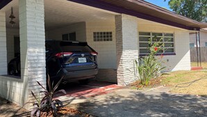 Een huis met een garage, een geparkeerde SUV en een plantje in de oprit.