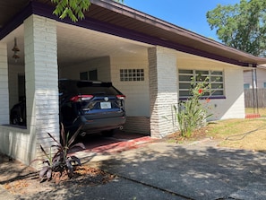 A house with a garage, a parked SUV, and a small plant in the driveway. - Classic Florida 2-bedroom house with AC in quaint DeLand (DeLand)