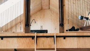 Une pièce de style loft avec un plafond en bois, un télescope et une échelle.