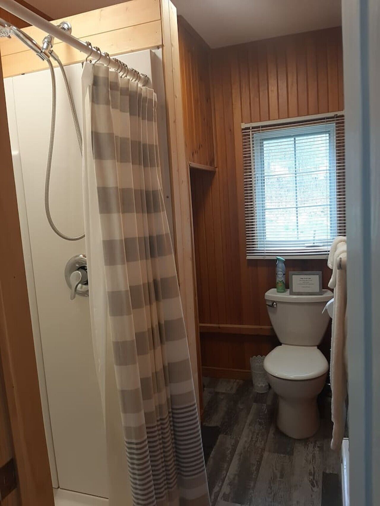 Een badkamer met douche, toilet en raam.