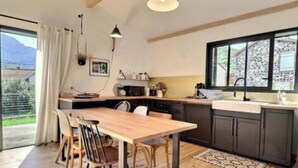 Eine moderne Küche mit Esstisch, Stühlen und einem großen Fenster.